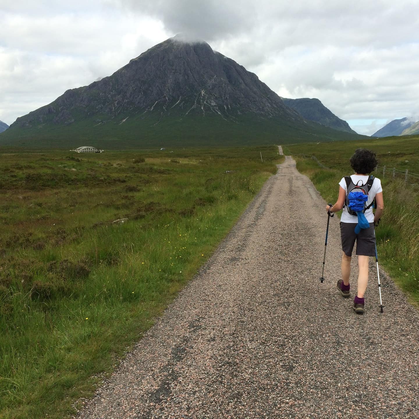 A woman hikes an empty trail beneath a mountain in Glencoe.