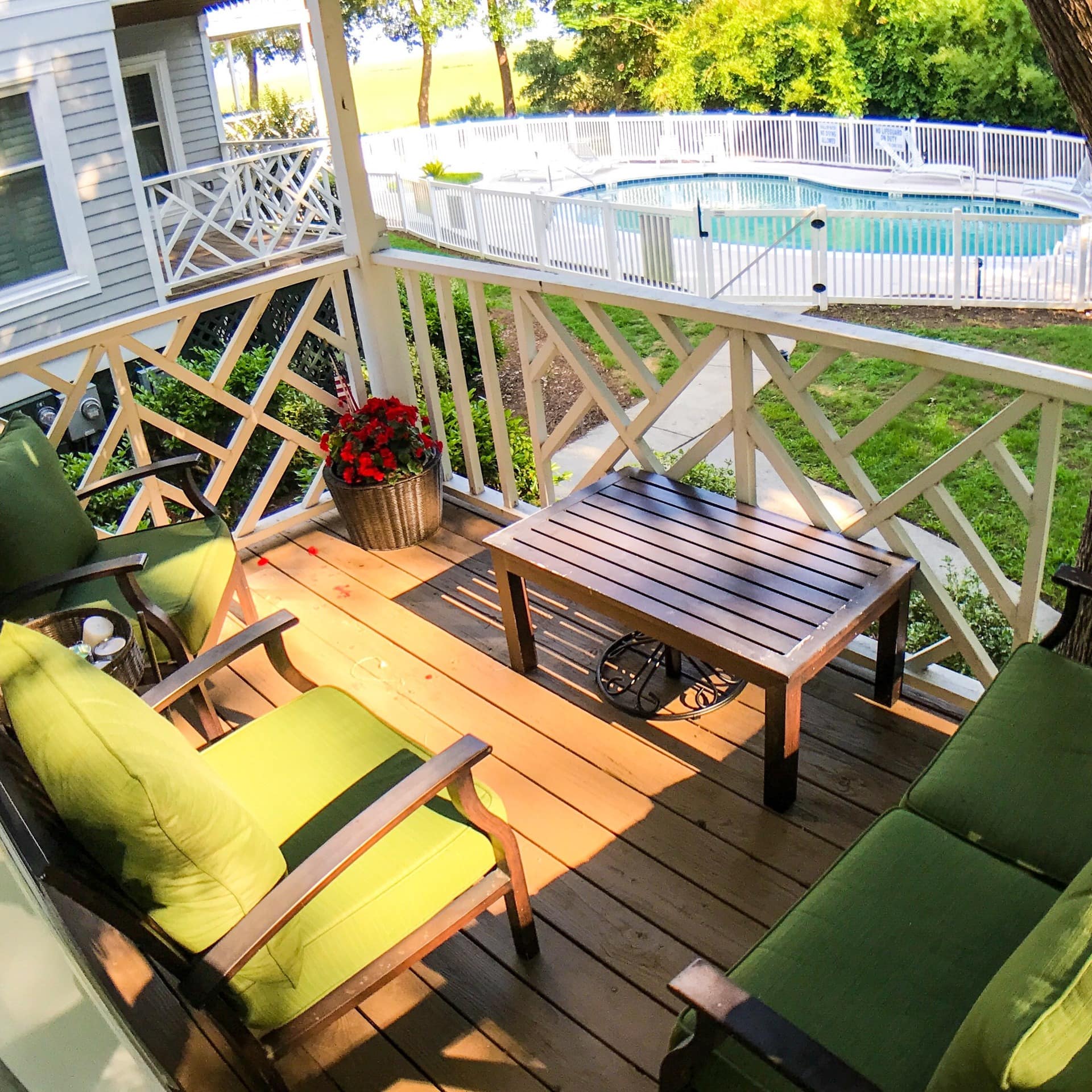 Outdoor seating on a pet-friendly rental's covered deck, which overlooks a fenced swimming pool in the backyard