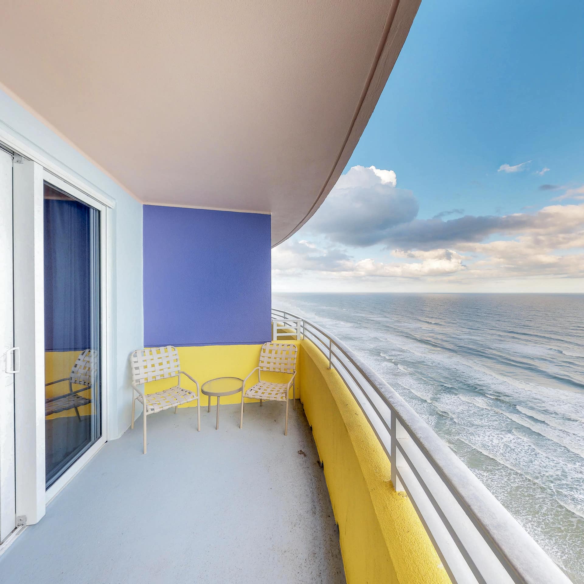 Waves roll in beneath a yellow and blue balcony