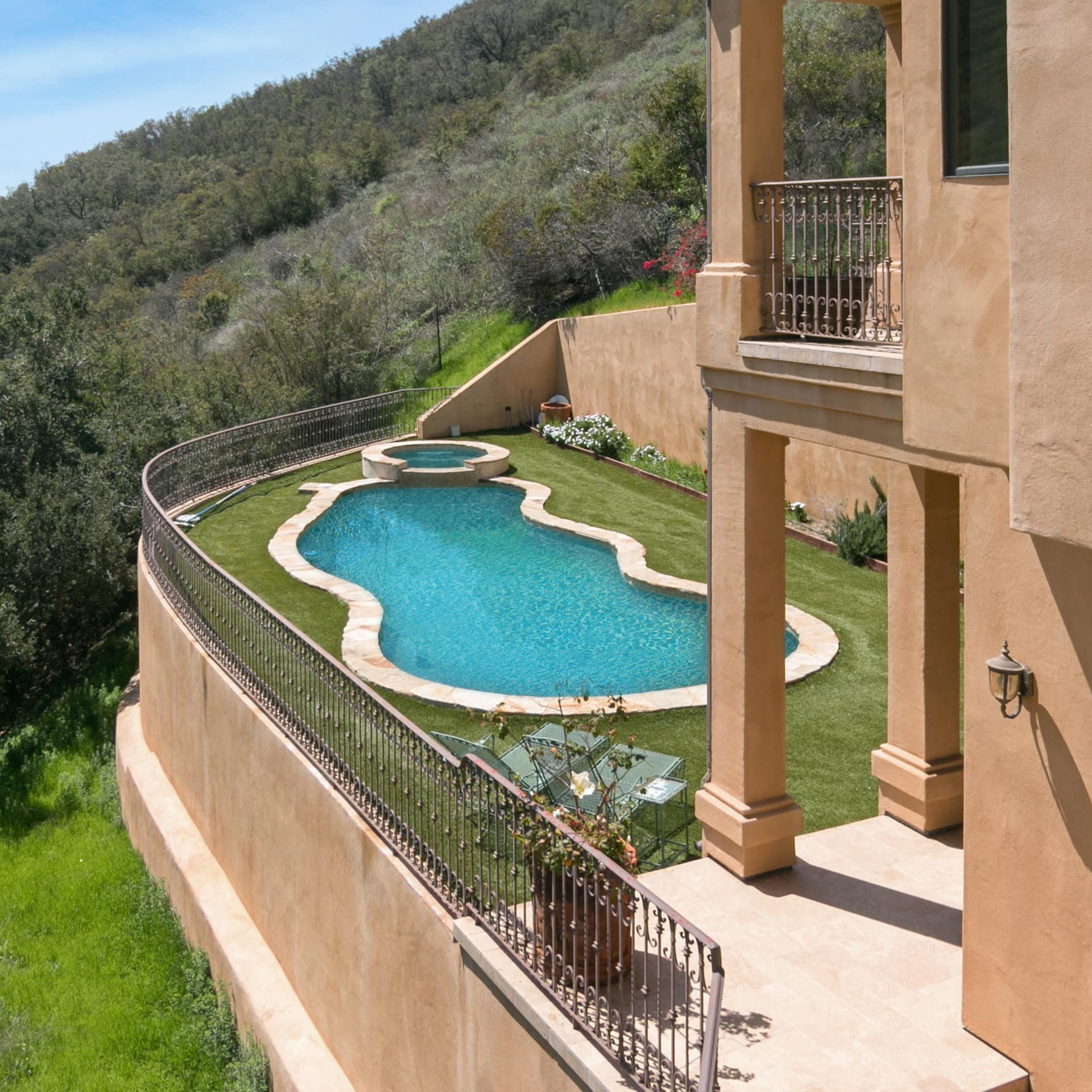 A palatial villa nestled on a hillside, with an outdoor pool and hot tub
