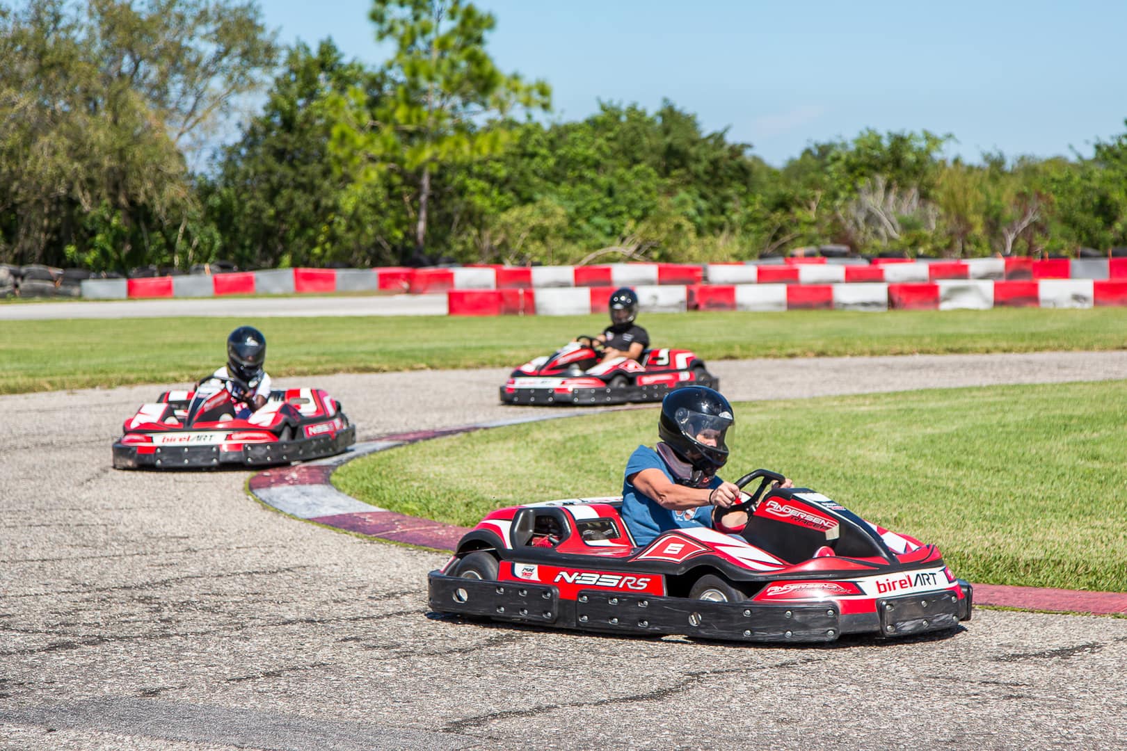Three people racing around the track at Andersen Racepark in red go-karts