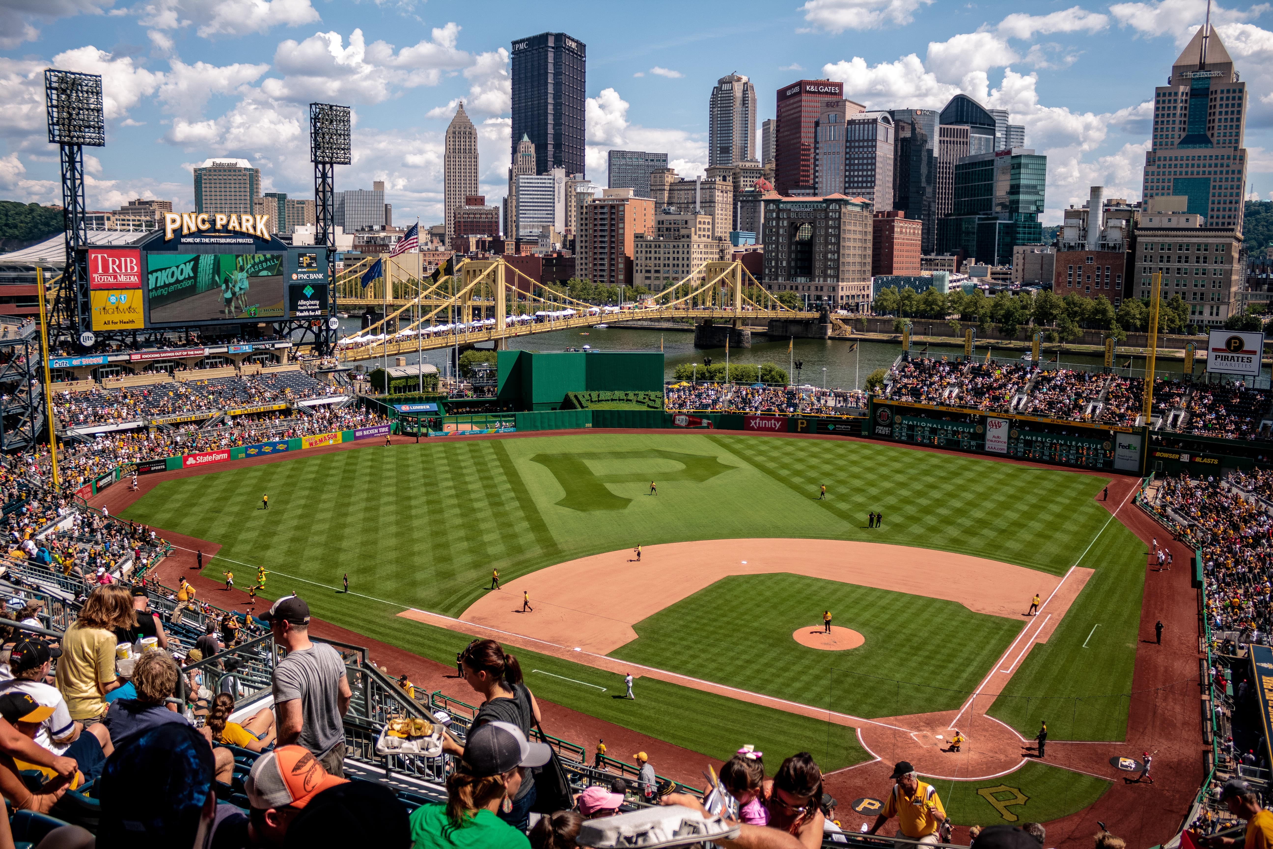 A well-attended baseball game at PNC Park, with buildings, the Andy Warhol Bridge, and the Allegheny River in the background