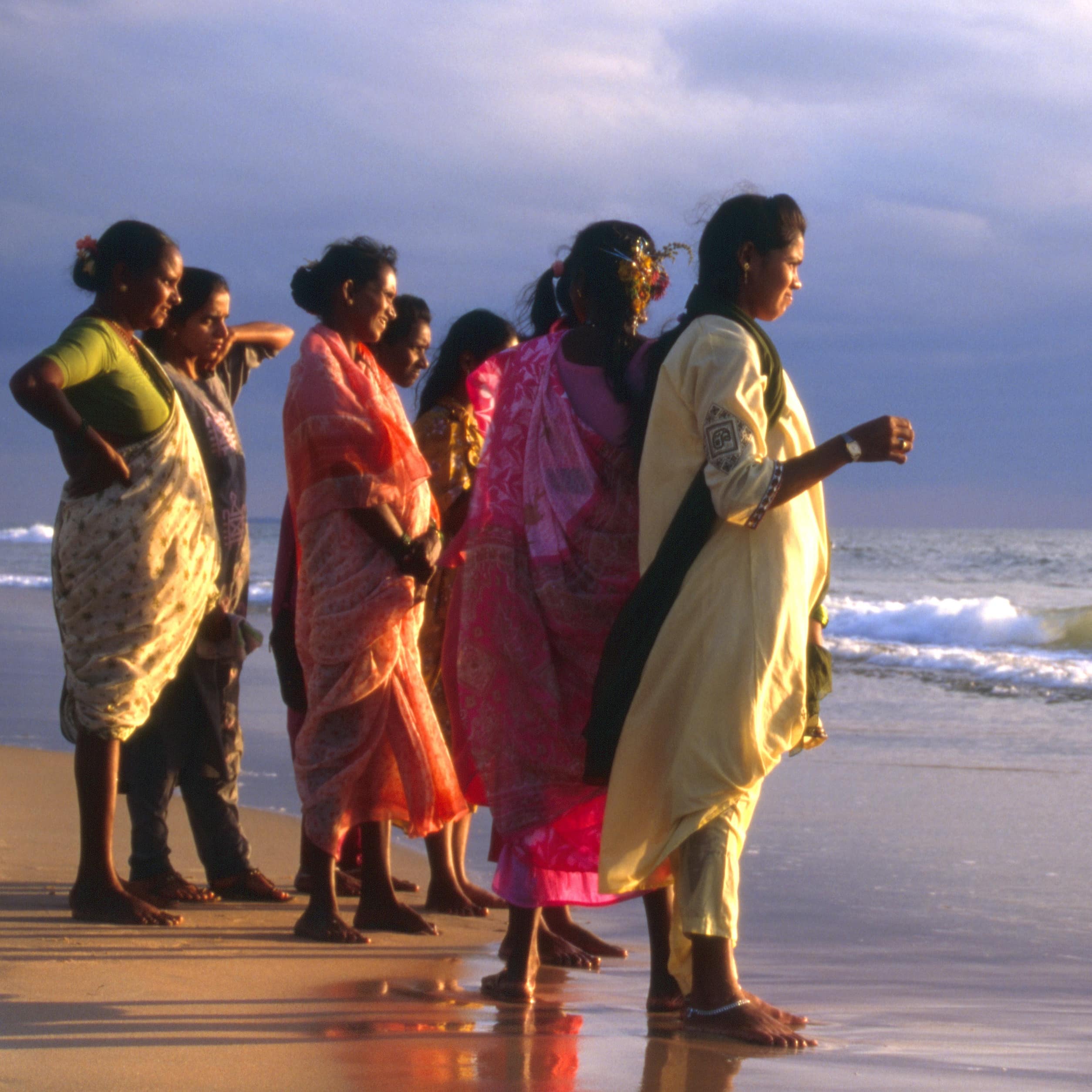 Women in traditional dress stand on the beach in Goa