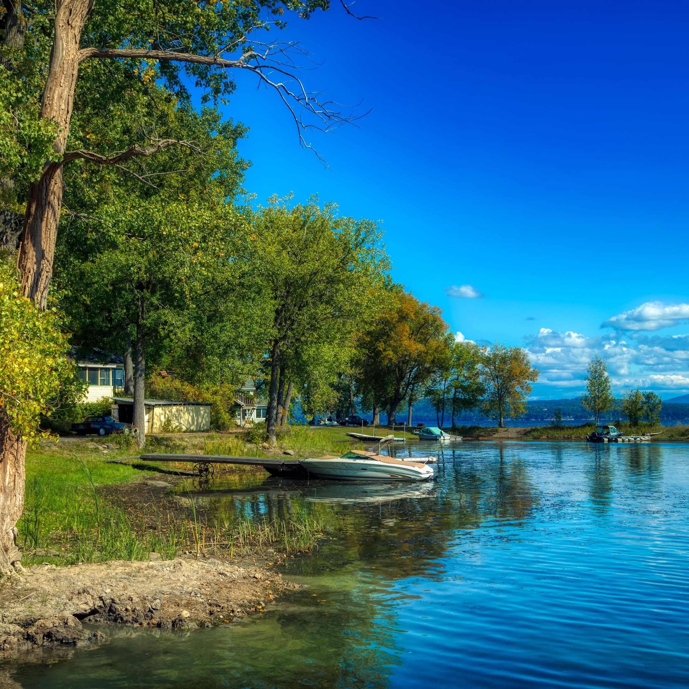 Small cabin overlooking a lake on a summer's day with boats in the foreground