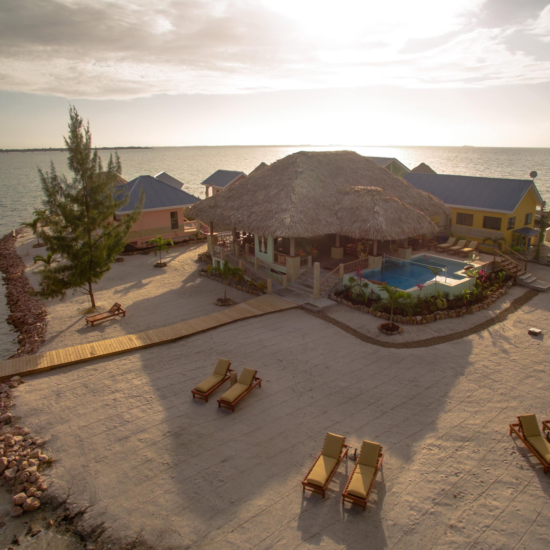 A private island rental with a private pool and deck chairs in its sandy garden