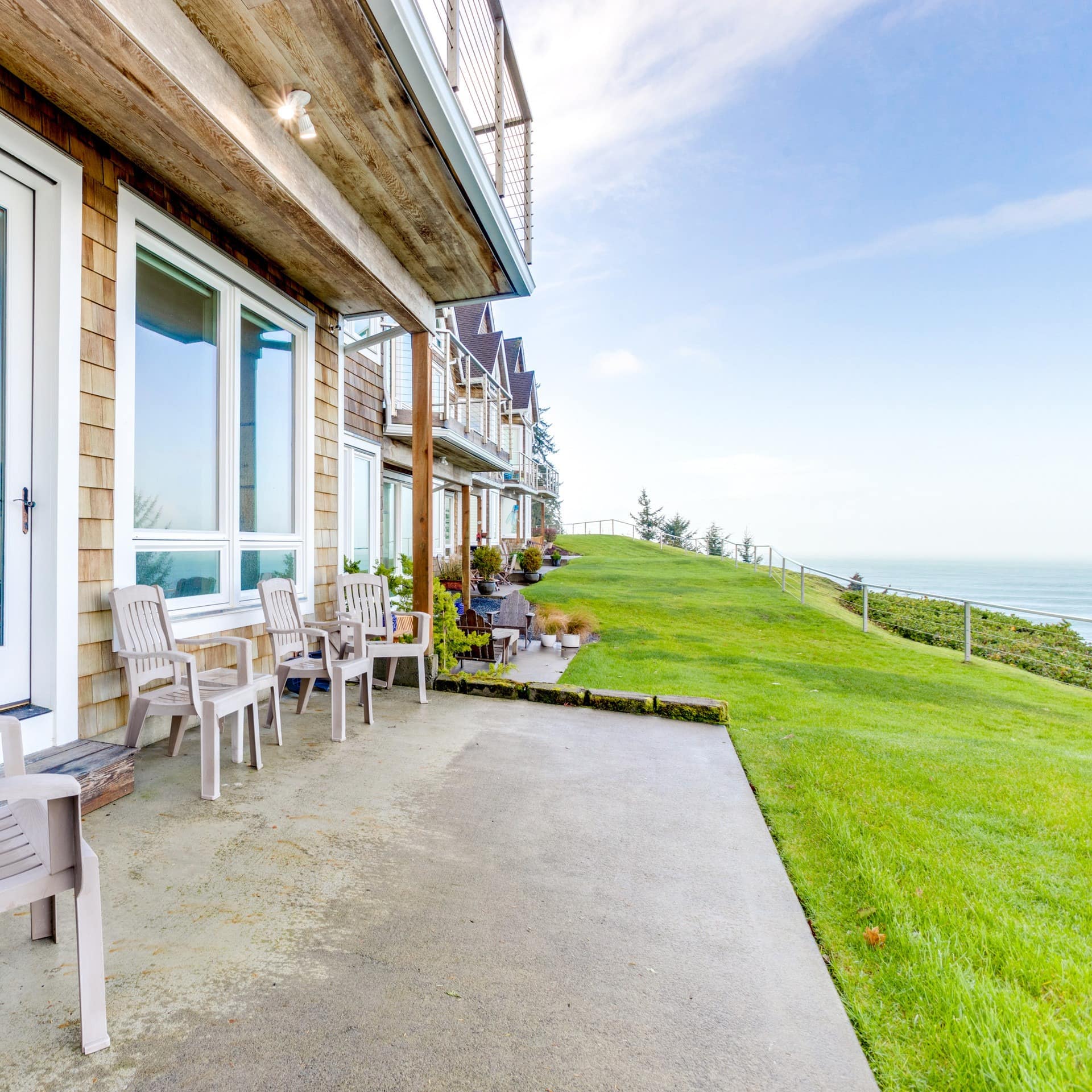 A plush patio with chairs spills out of a Seaside vacation rental to overlook the Pacific Ocean