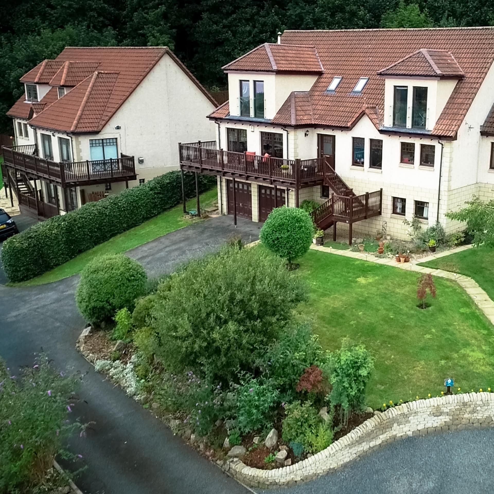 Homes with porches and steep roofs sit in green lawns near Edinburgh