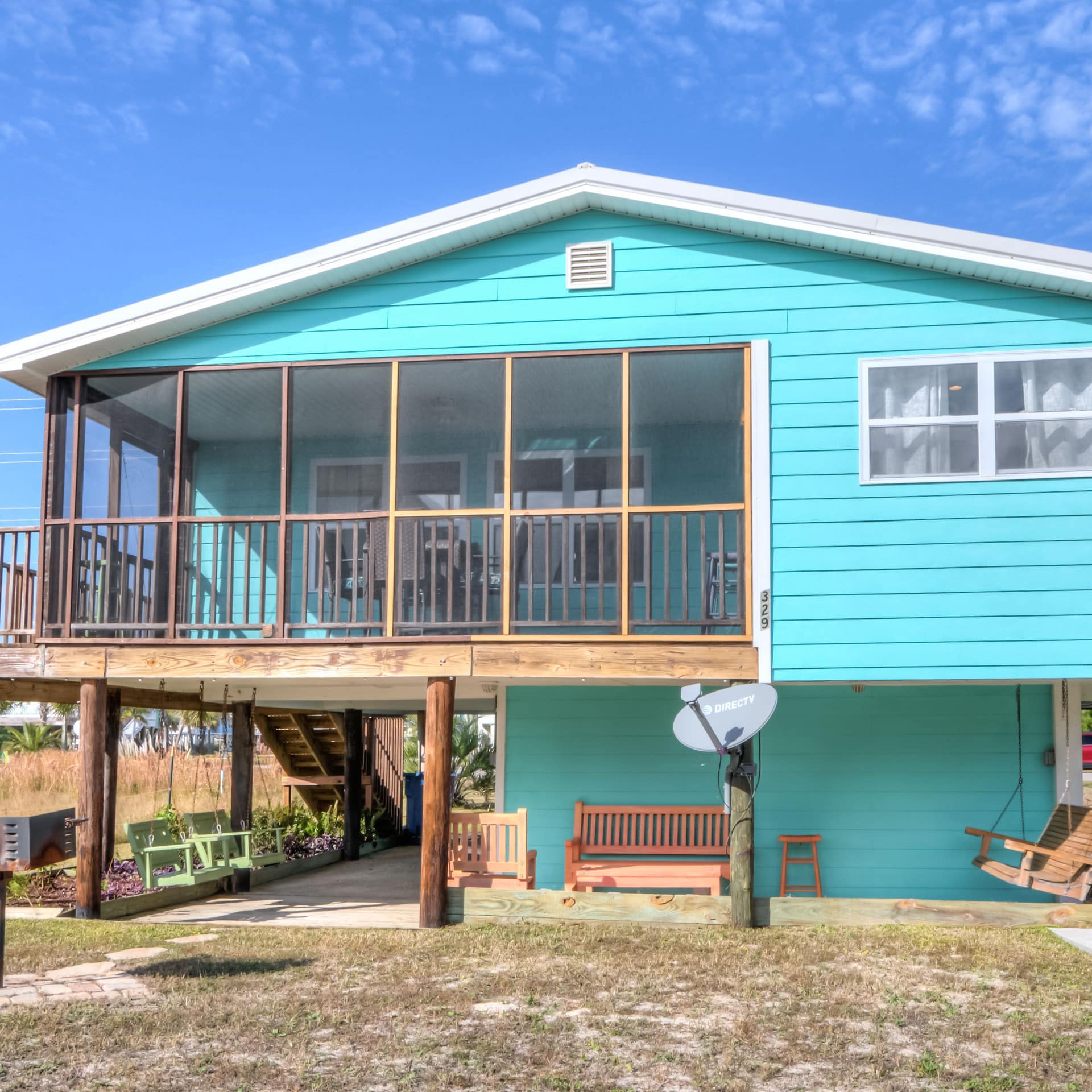 a vibrant turquoise home on stilts by Gulf Shores' beach