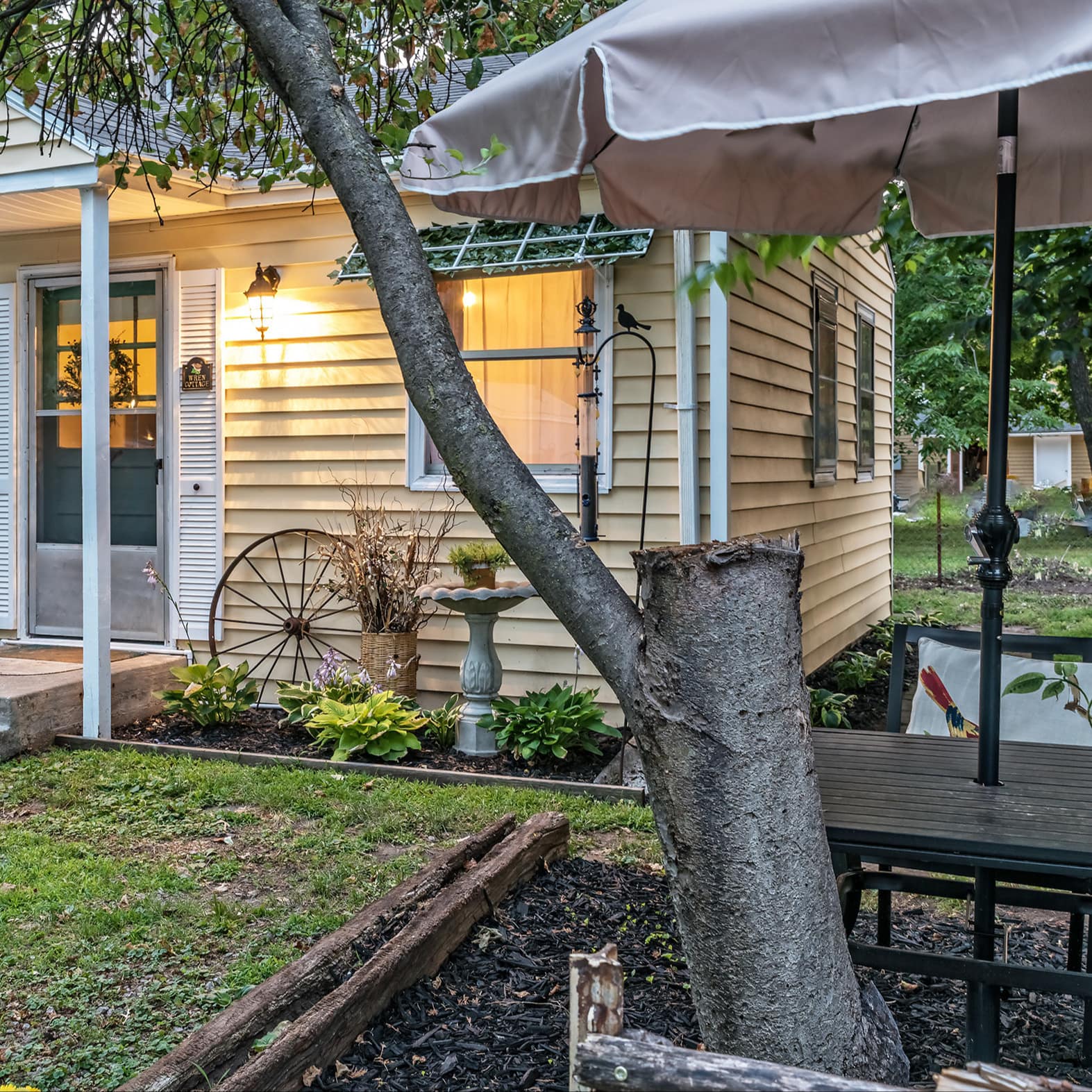 A small guest house with a garden and outdoor table underneath a tree in Kansas City