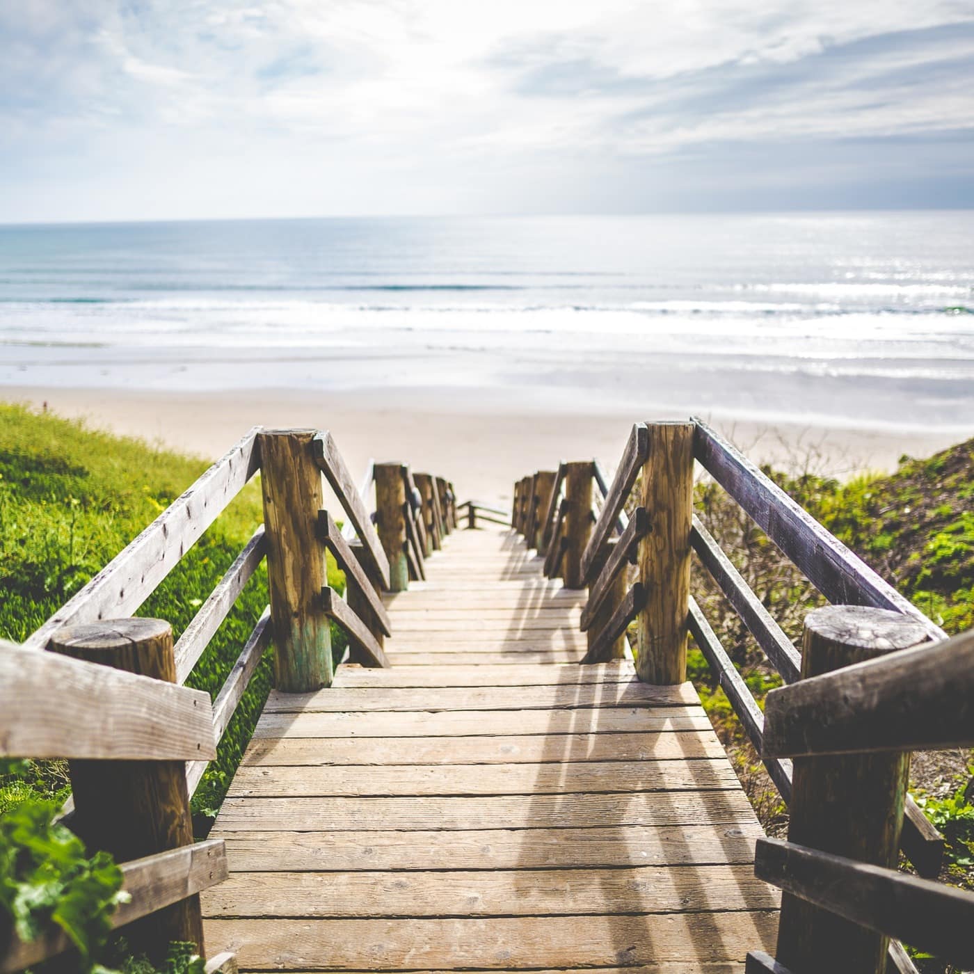 A boardwalk staircase leads to a lovely beach with rolling surf