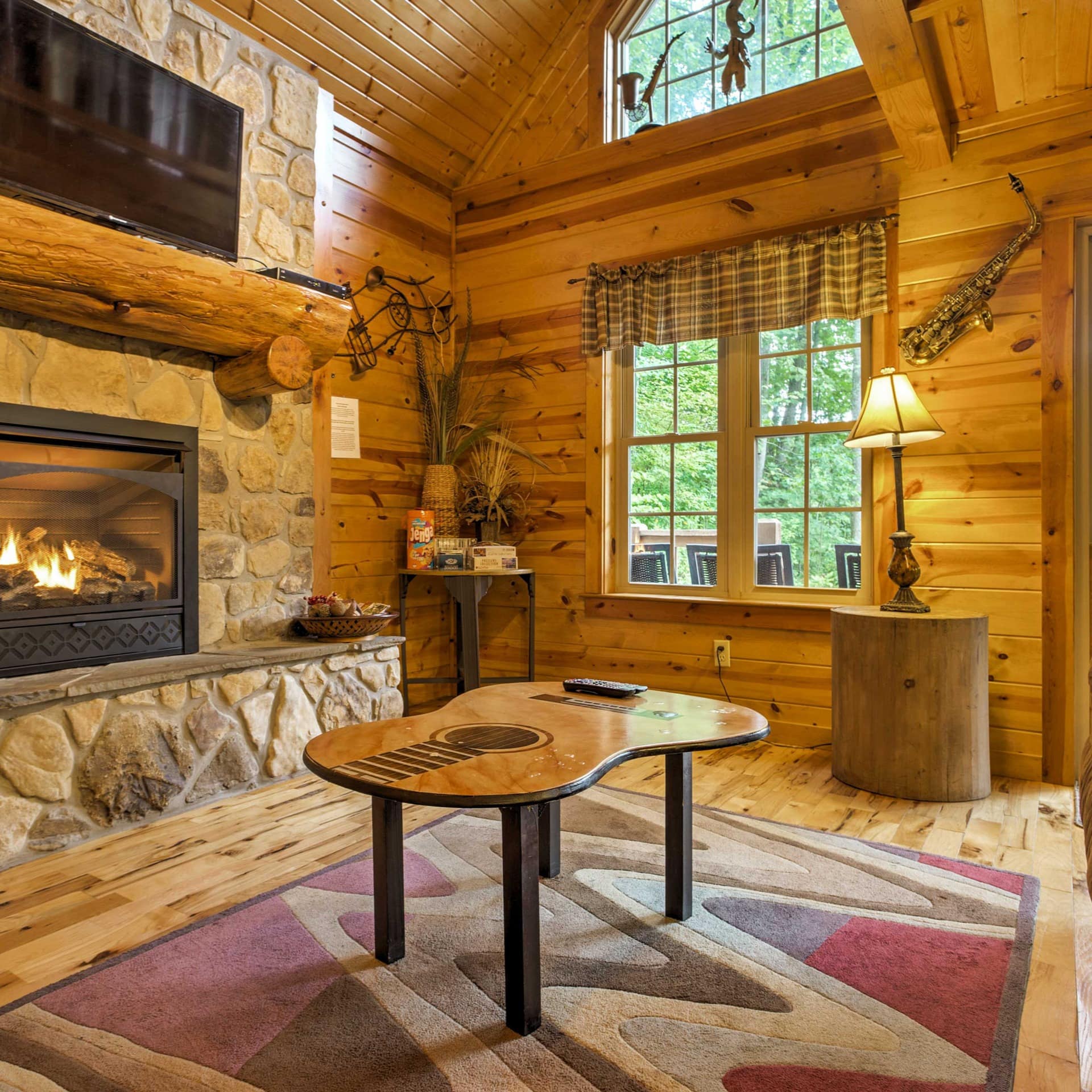 Wooden-walled sitting room with fireplace, high ceiling, and forest views