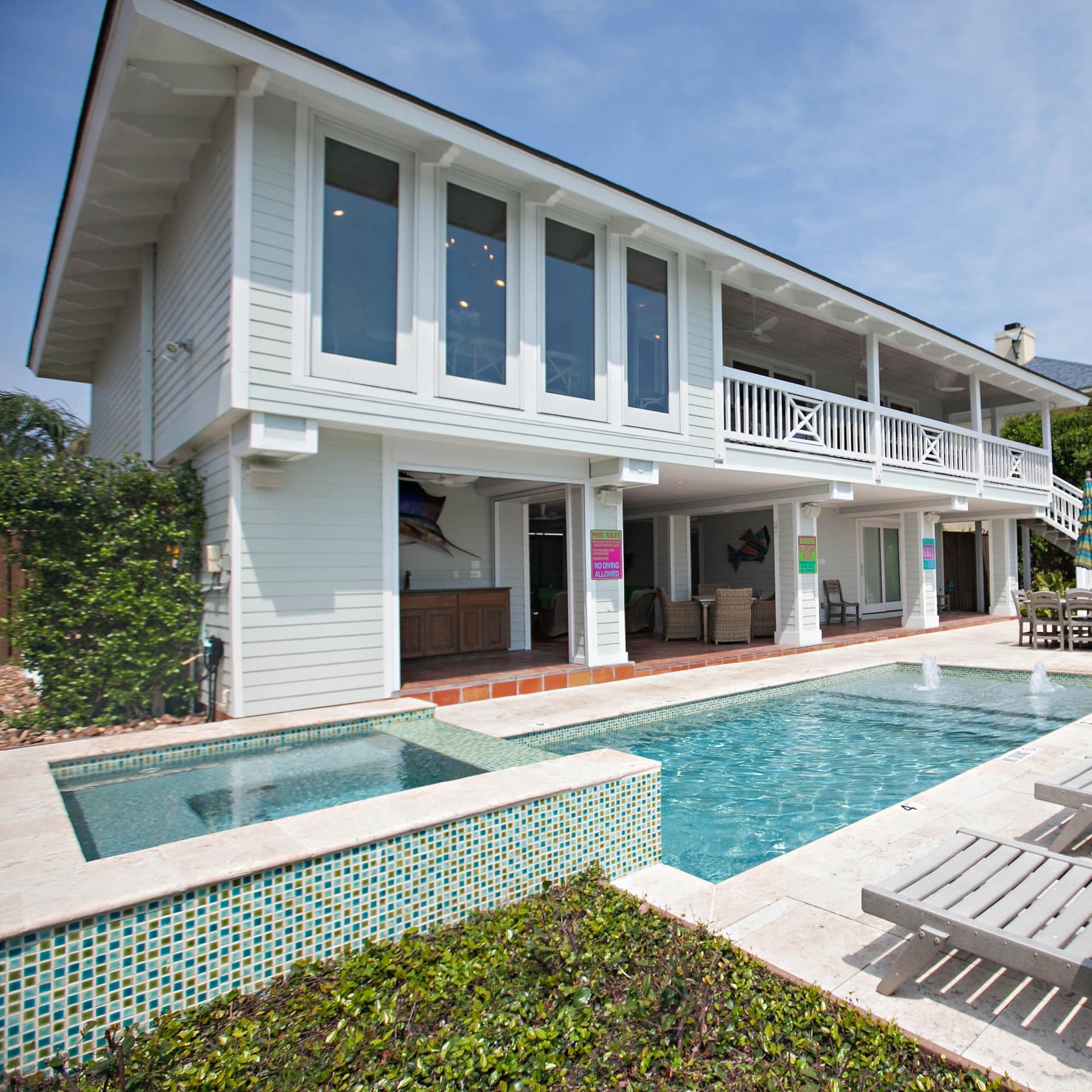 A luxurious beach rental in Texas with a pool and sunbeds outside a handsome exterior