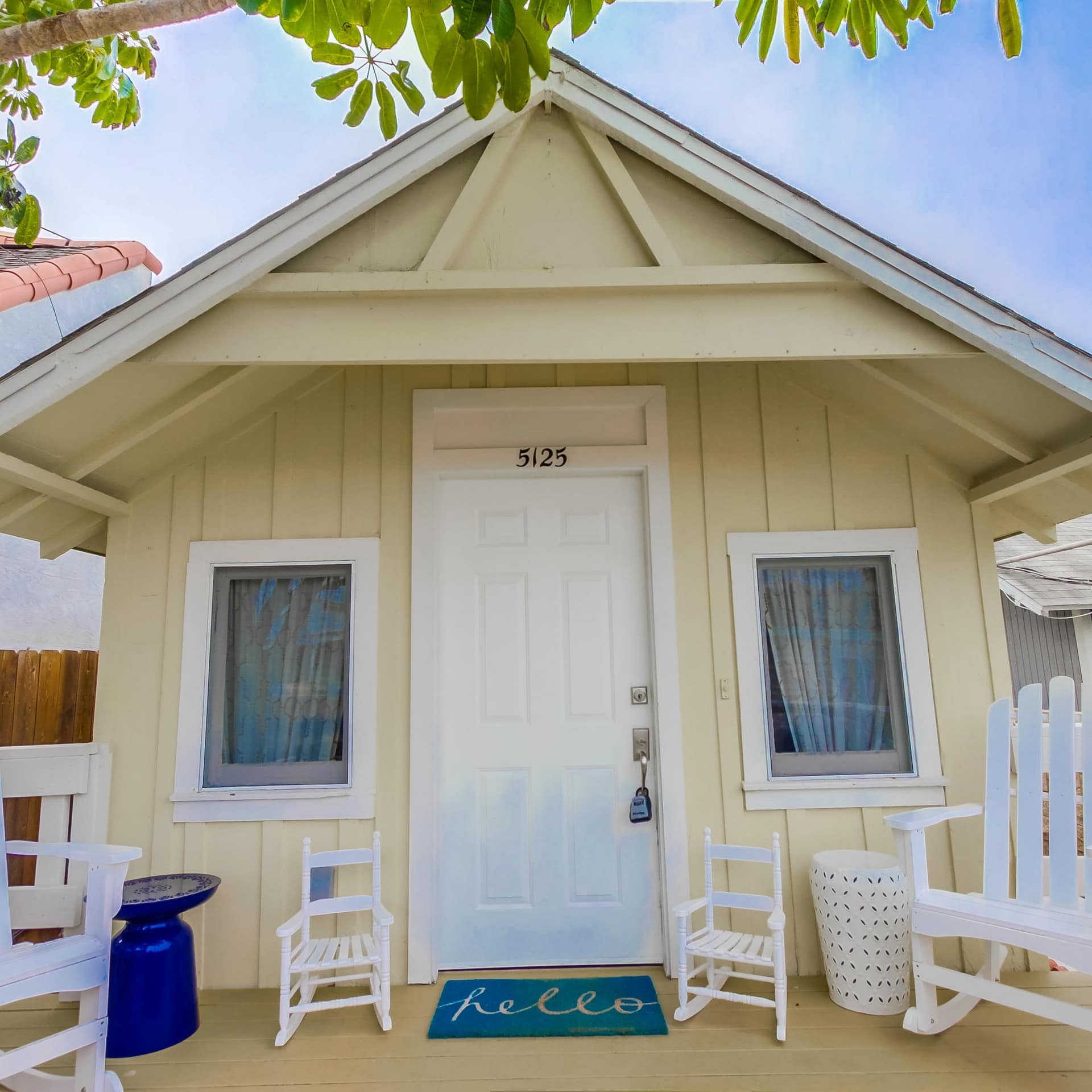 A beach cottage with a charming Californian style fronted by a porch with white chairs
