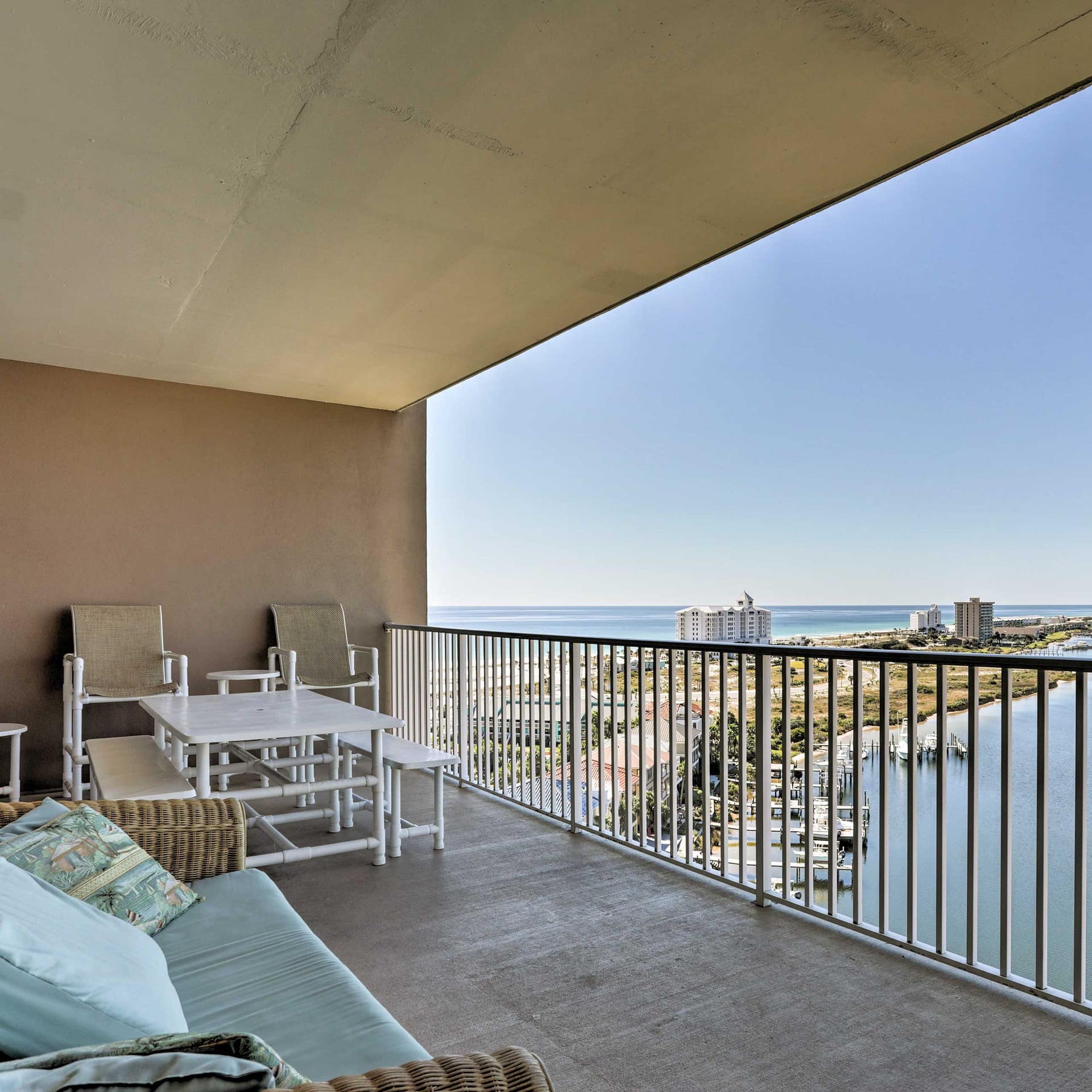 A balcony with a view of the lagoon and Pensacola Beach, filled with outdoor furniture