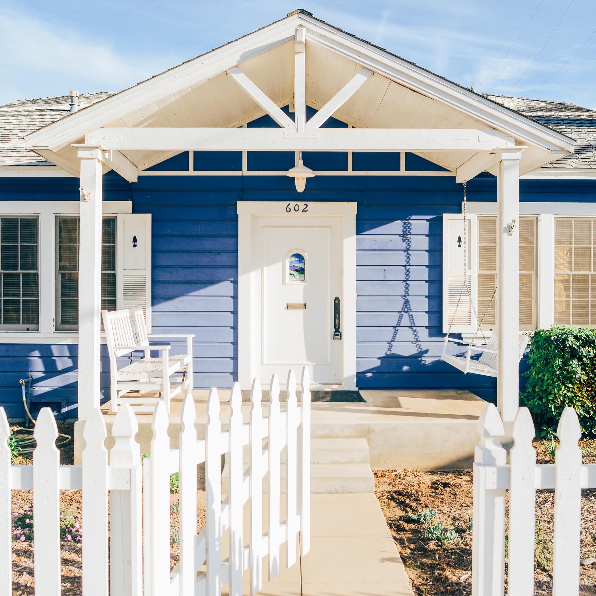 A cute cottage with blue-painted walls and white picket fences