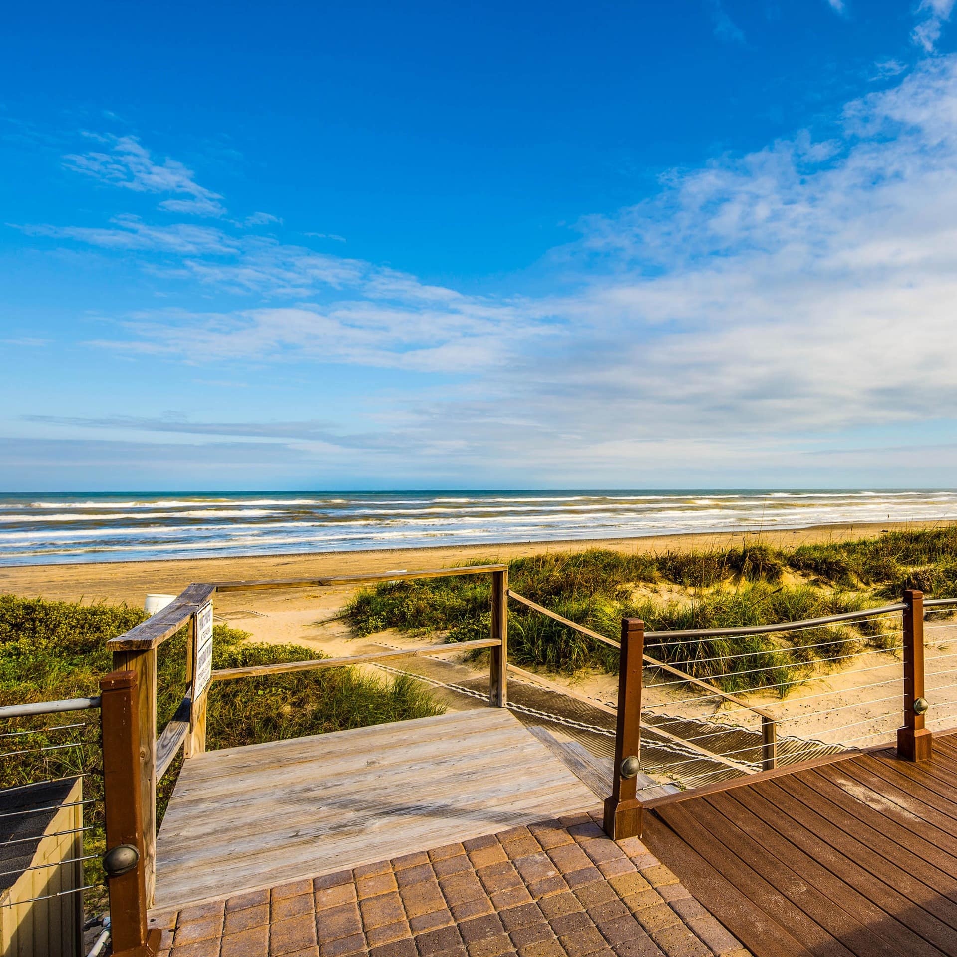 The golden beaches and grass-topped dunes that run outside a South Padre Island rental