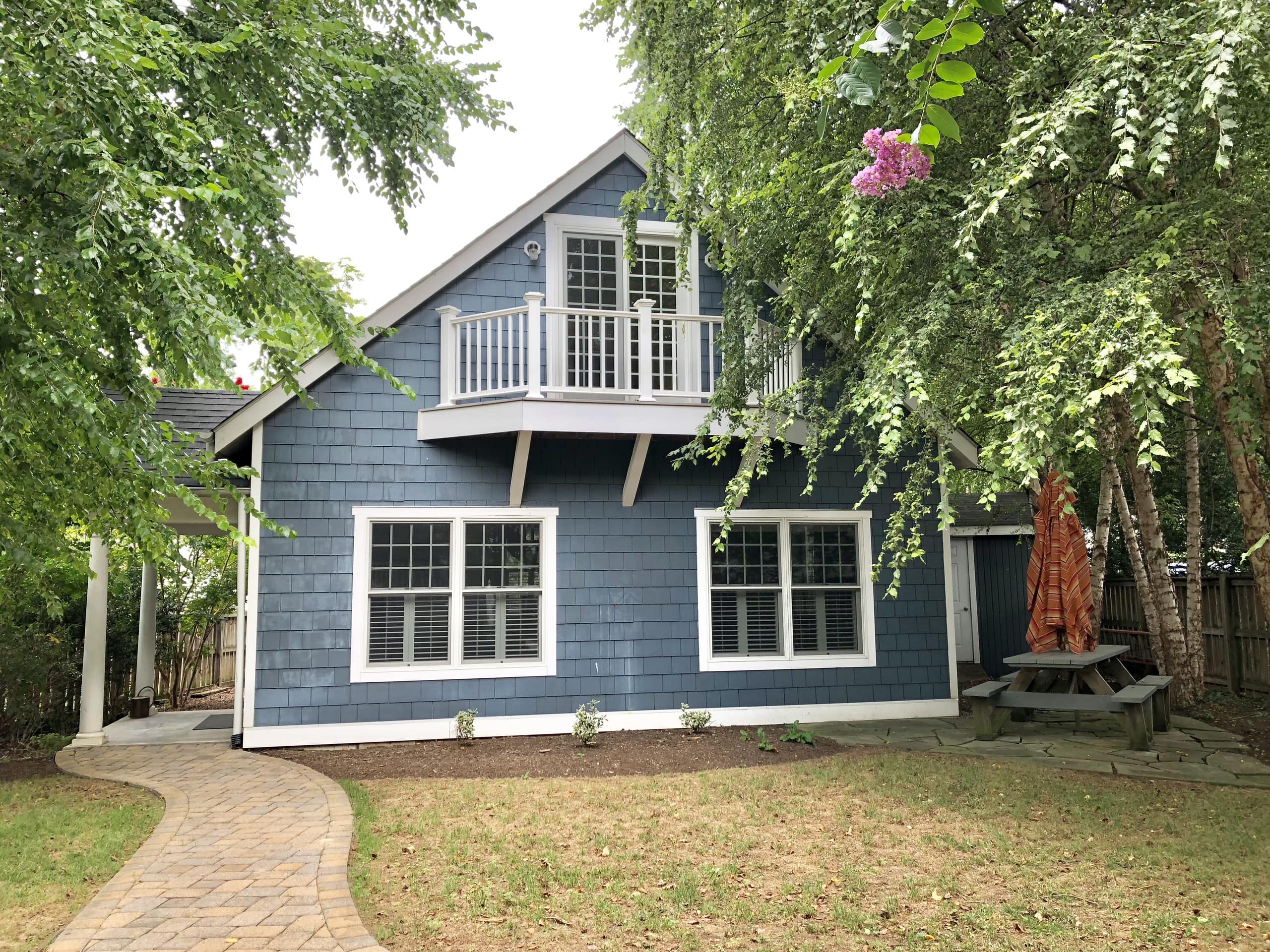 A blue-painted cottage has a winding walking path leading to its porch