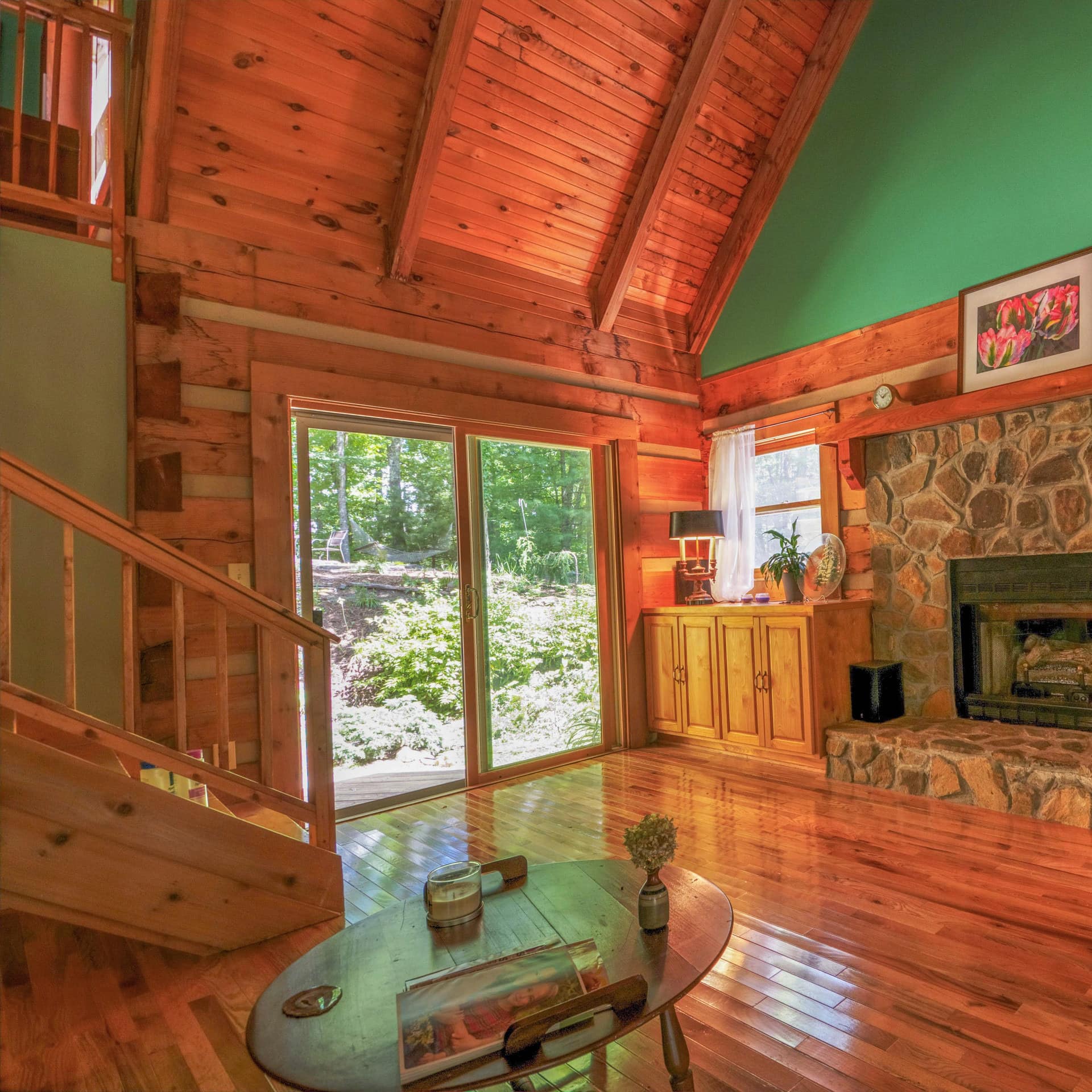 This Boone cabin rental's living area features hardwood floors, a stone fireplace, and a high wooden ceiling.