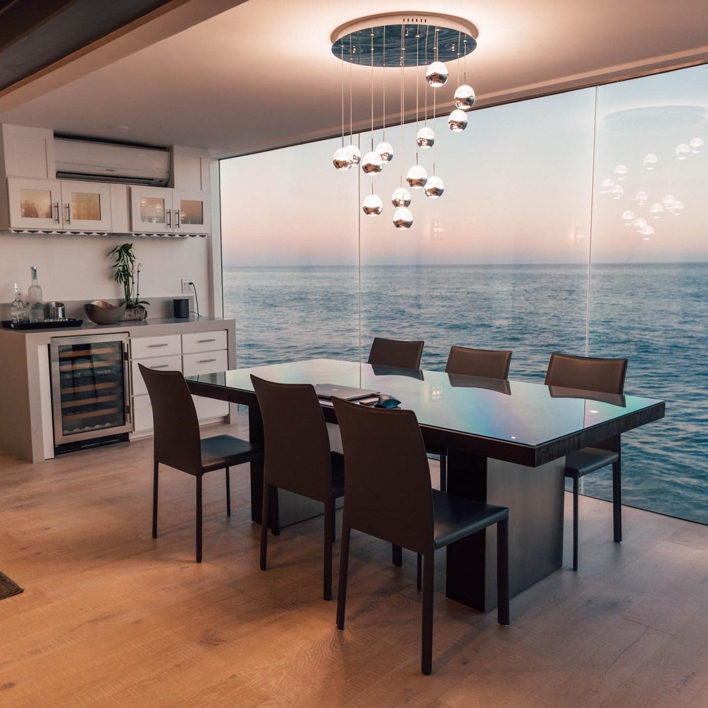 The inside of an exclusive and modern Malibu beach house with floor-to-ceiling windows overlooking the ocean