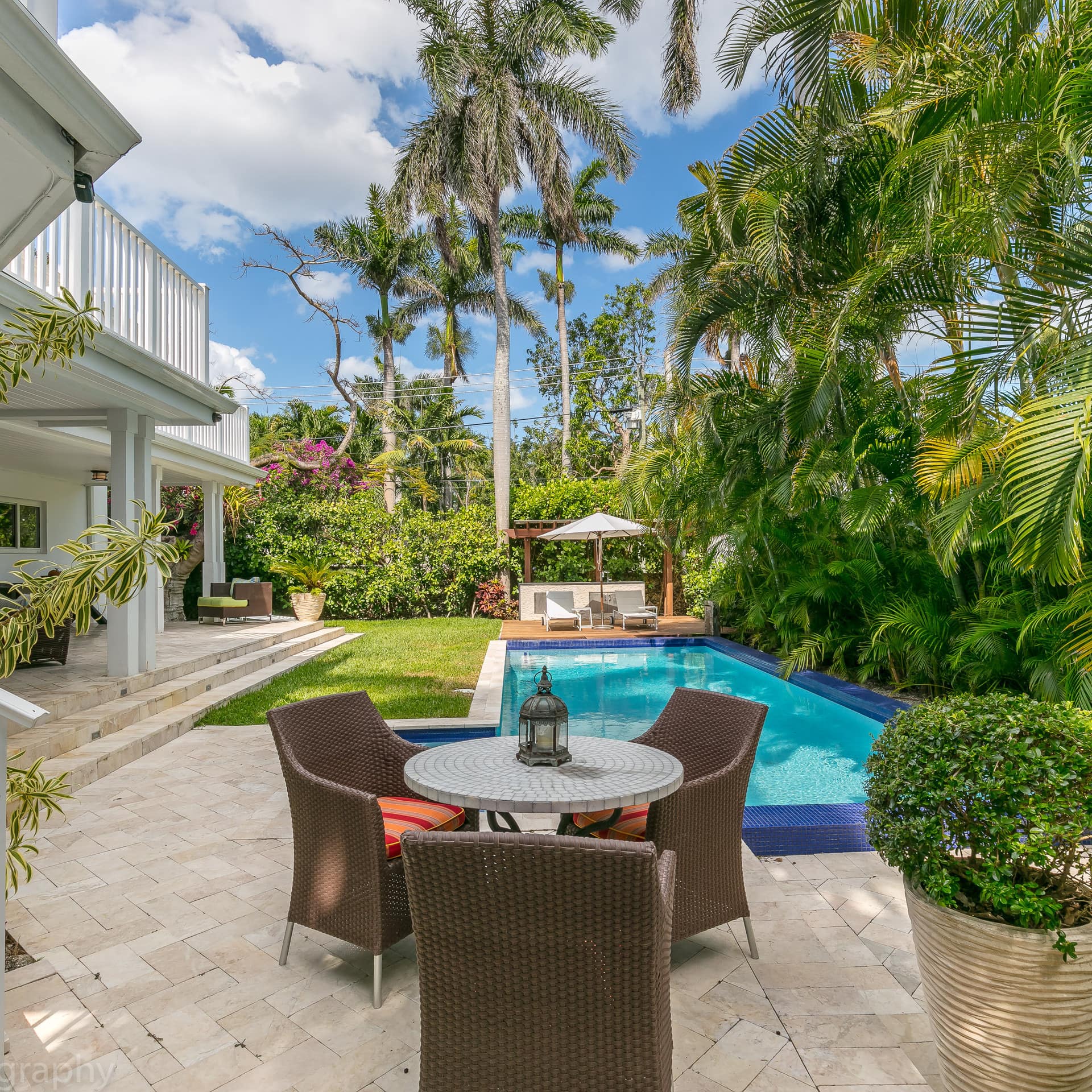 A luxury villa with a pool and seating area in a garden surrounded by palm trees in Coconut Grove