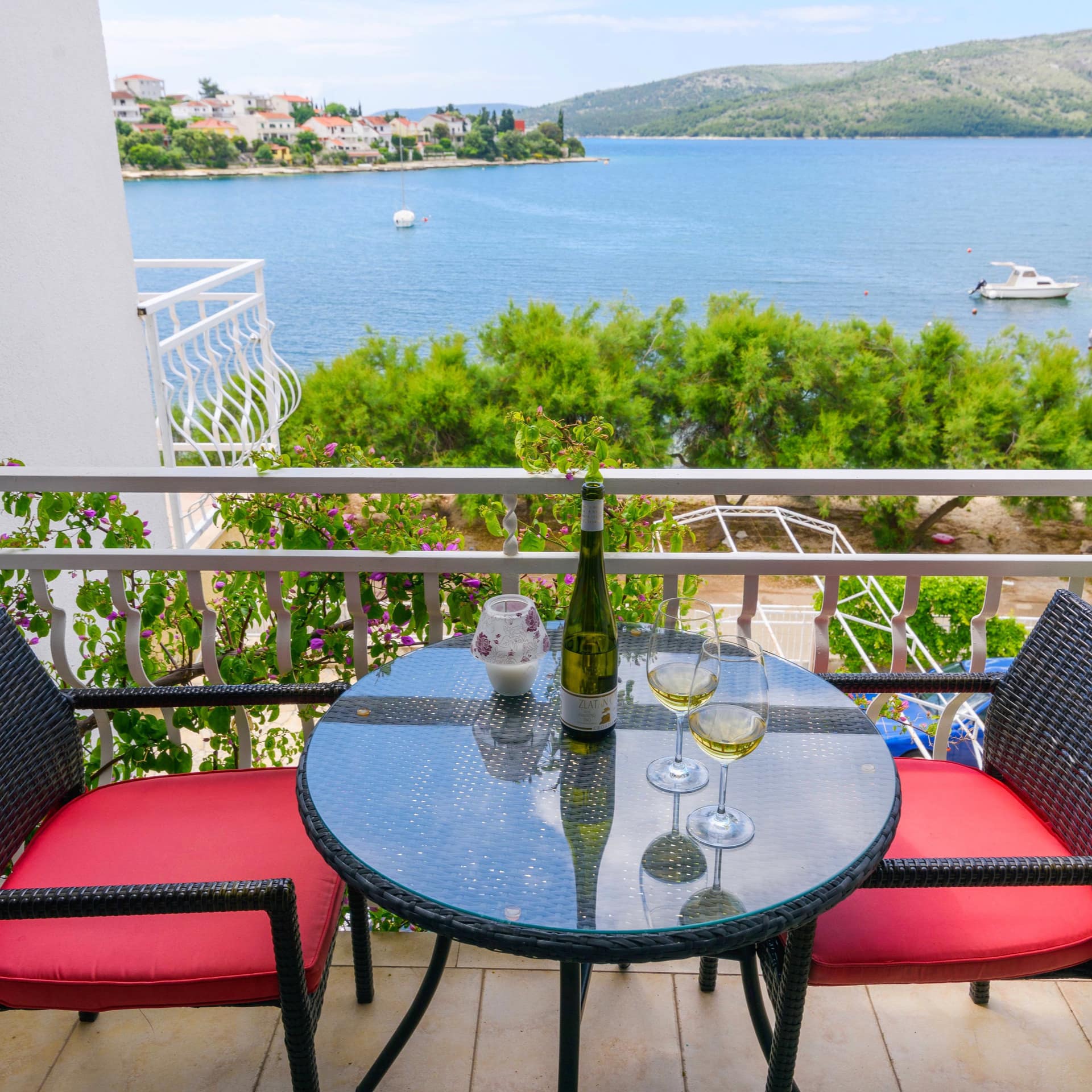 Two glasses of wine on a dining table for 2, set up on a Croatian villa rental’s sea-facing balcony