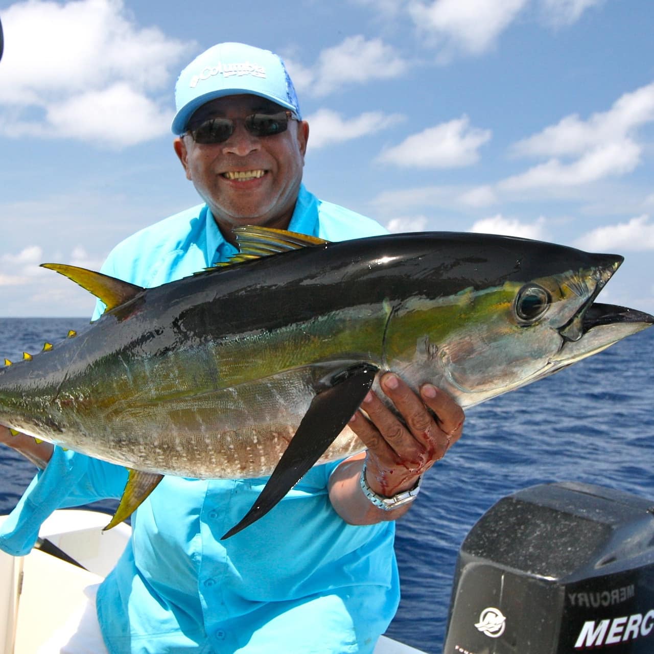 Smiling man on a boat holding up a large yellowfin tuna