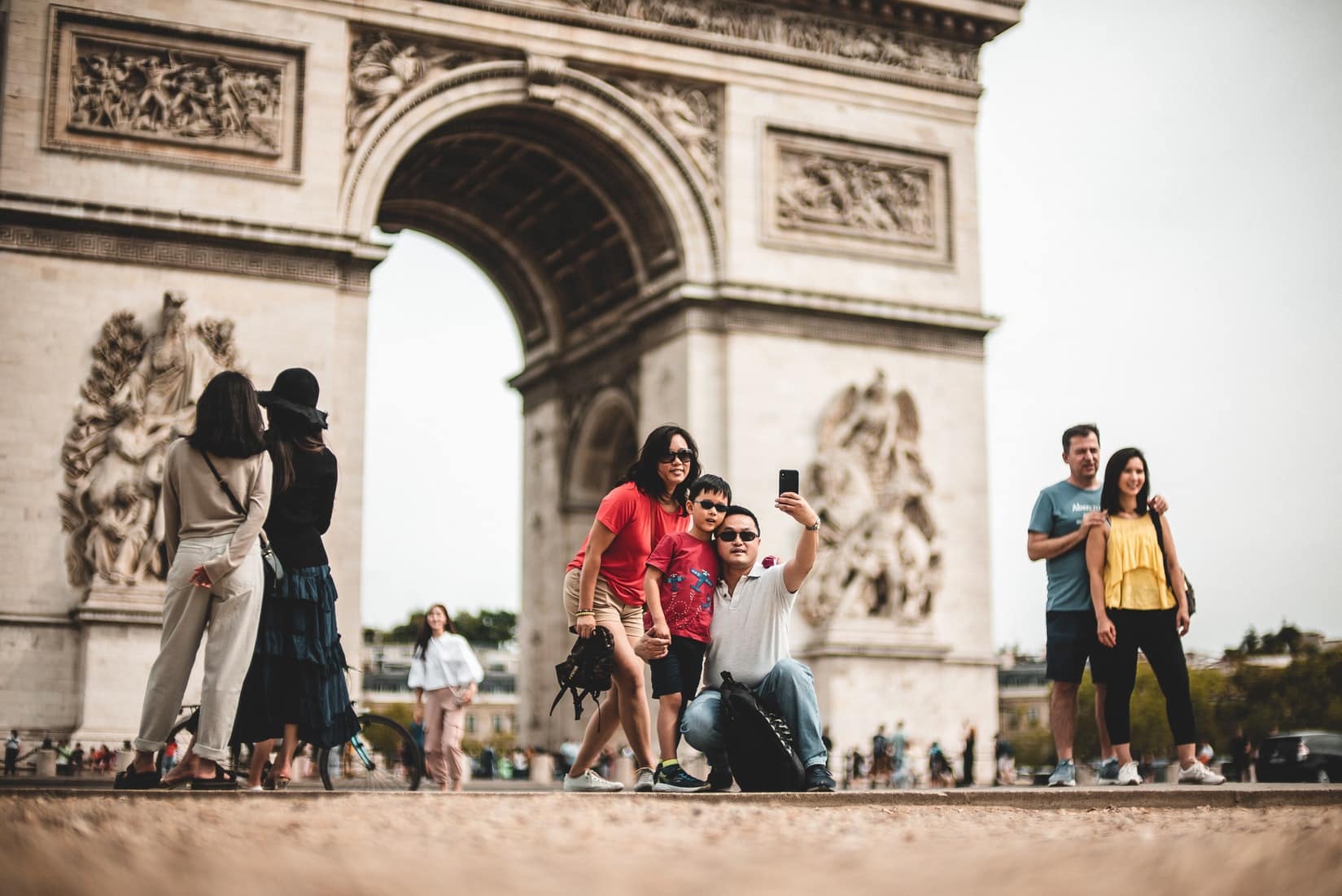 family taking a selfie in front of the arc de triomphe