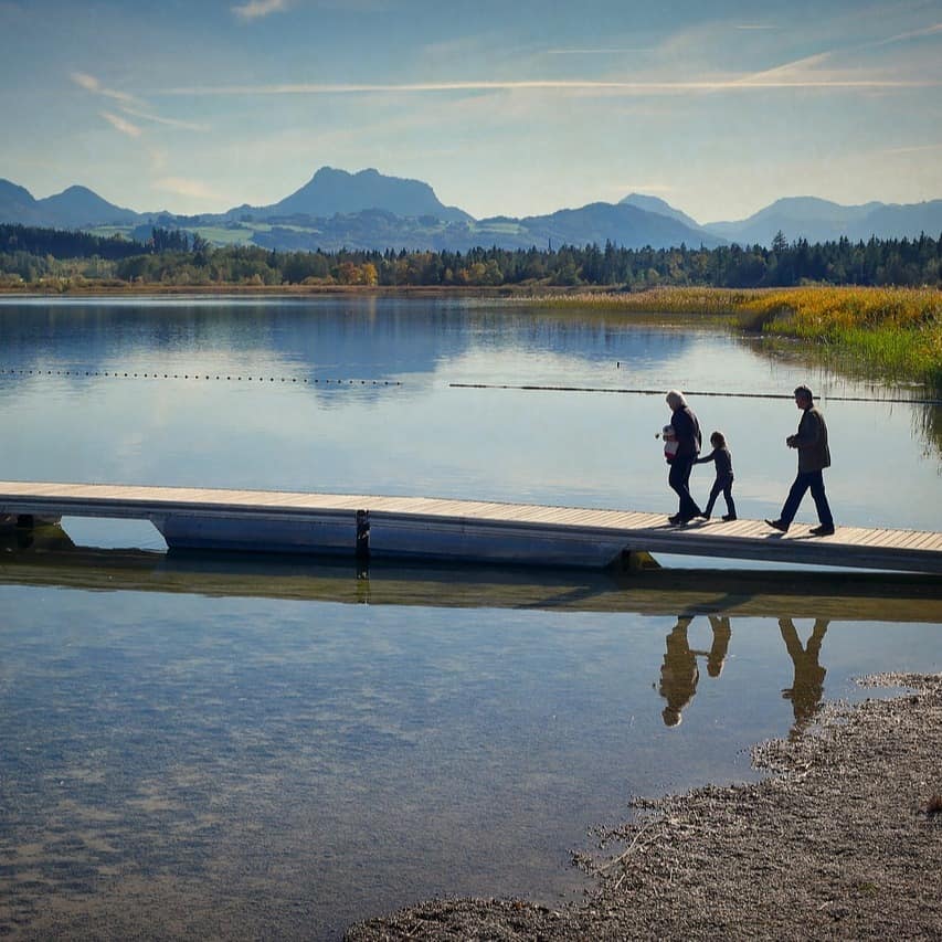 A family walking down a dock on a lake