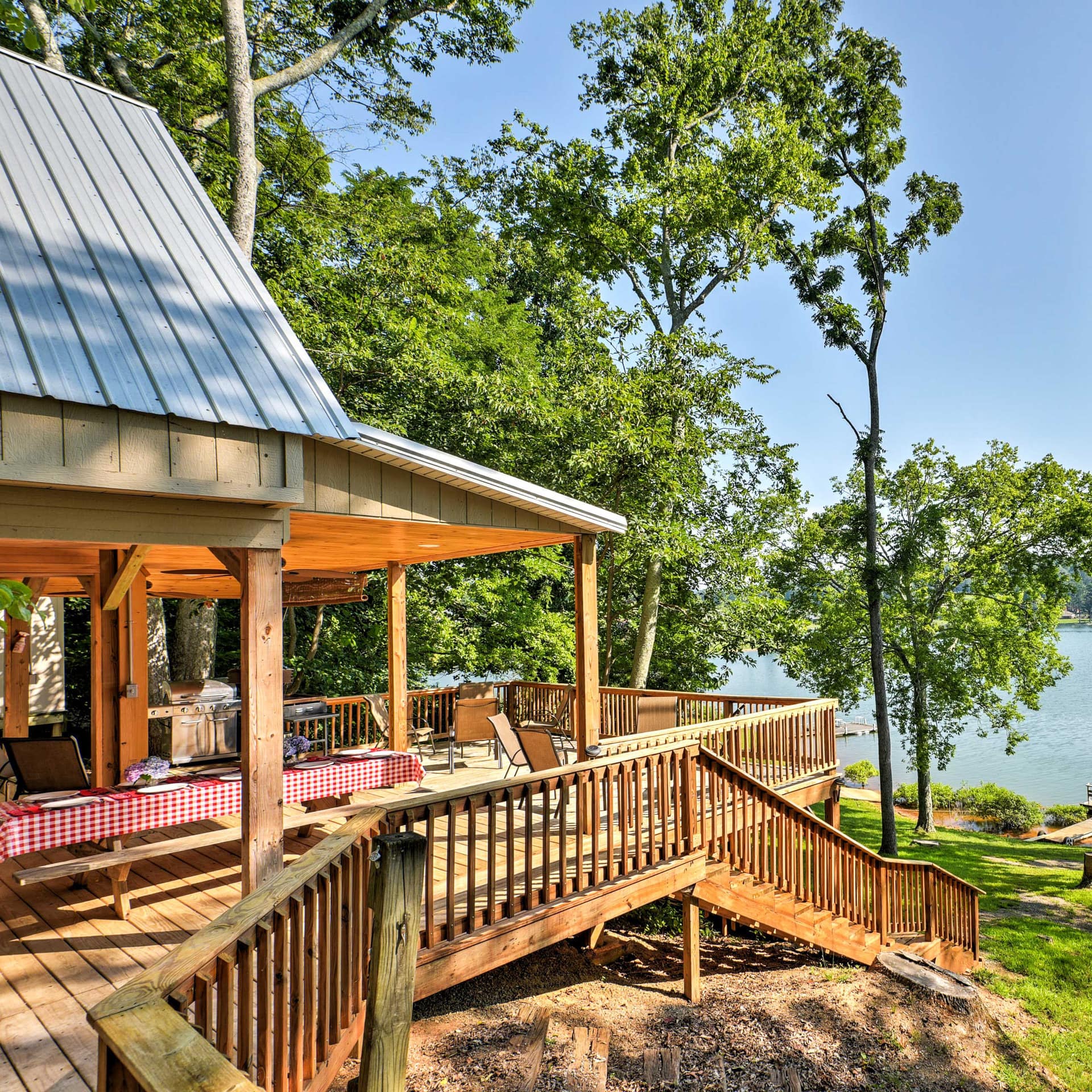A back deck and a private dock surrounded by trees overlooking a lake